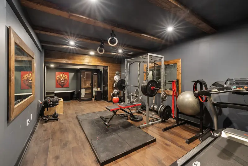 A home gym with a squat rack, bench and weights on a wooden floor