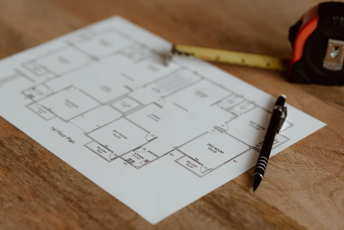 A room plan on a table with a tape measure and pen.