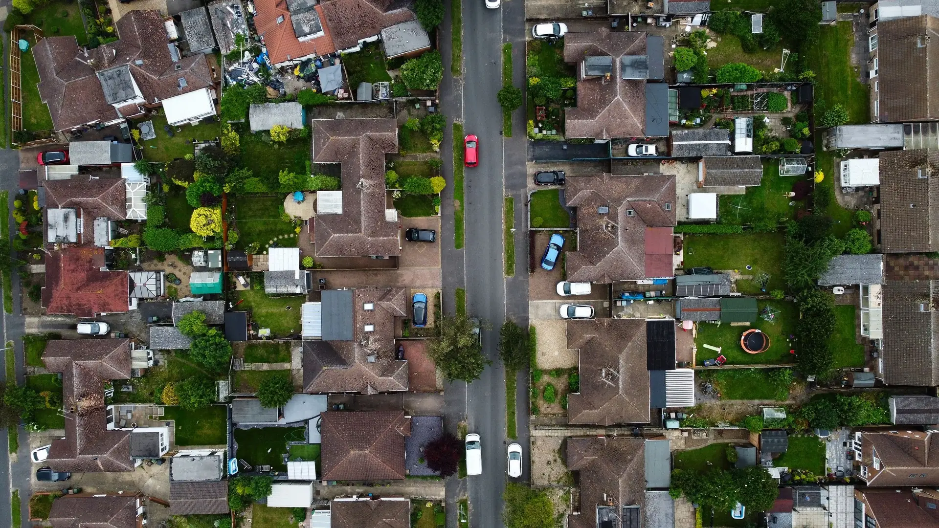 Looking straight down on a street of semi-detached houses with driveways and back gardens.