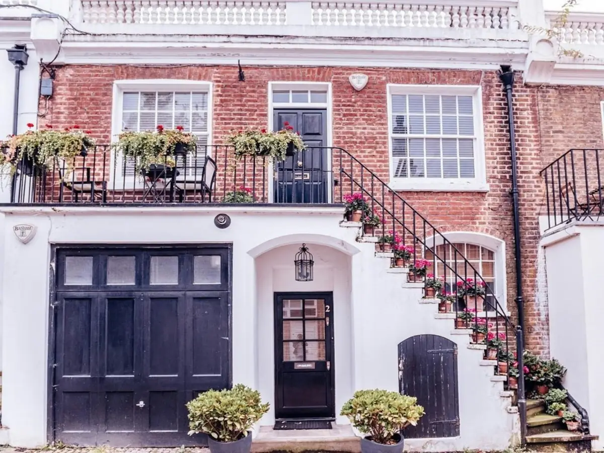 A mews house with a black garage door built into the ground floor.