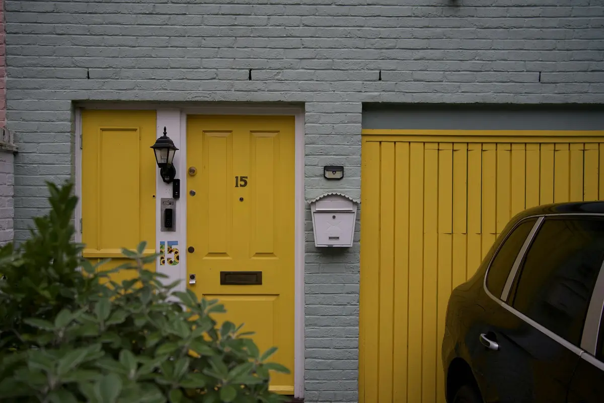 A house with a yellow garage door beside its yellow front door.