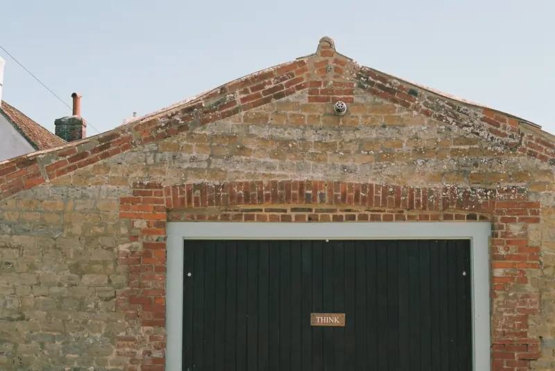 A brick garage with a dark green up-and-over door